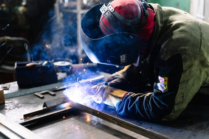 Opérateur soudant une barre de métal dans un atelier.